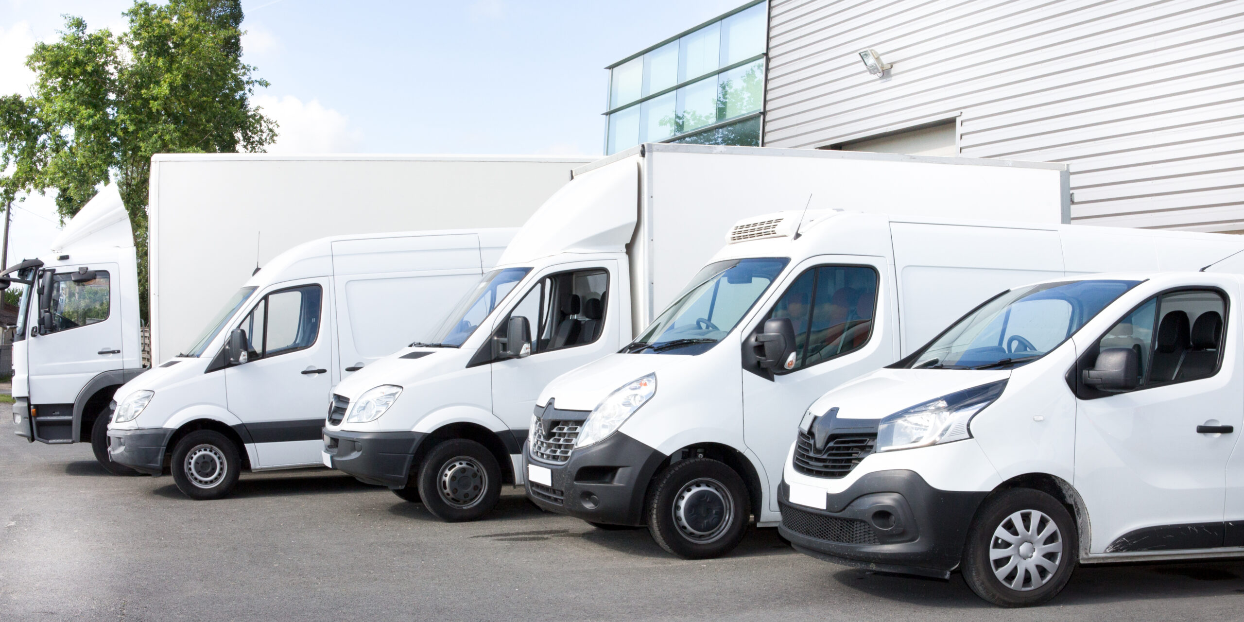 Image shows different delivery vehicles lined up outside a warehouse